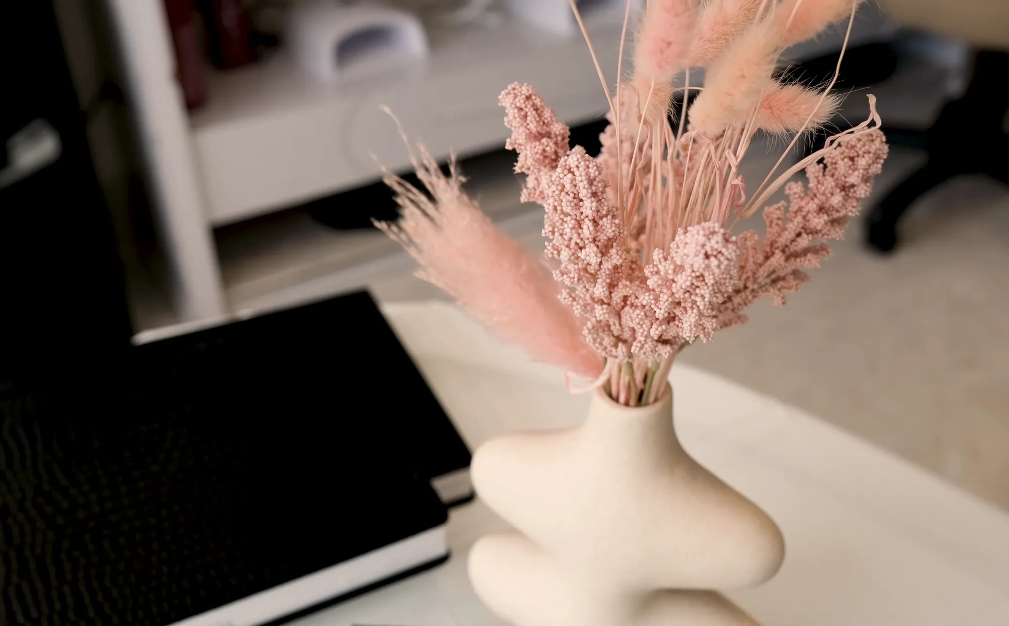 Dried pink pampas in a white ceramic vase at the manicure station